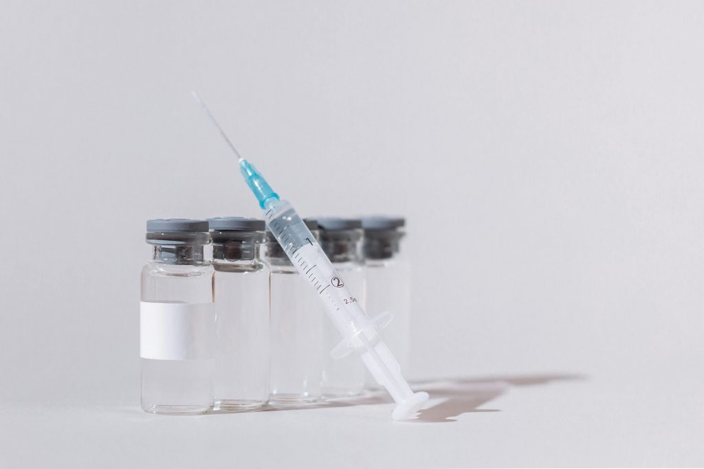 Close-up of vaccine vials with a syringe, emphasizing healthcare and vaccination.